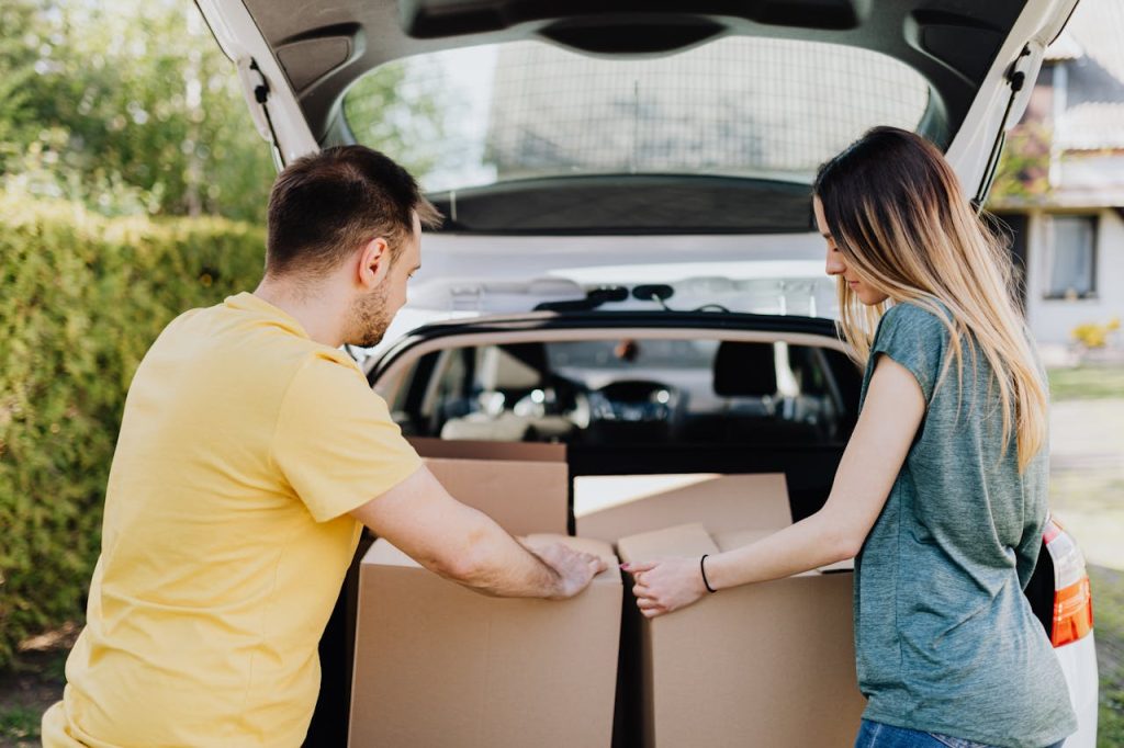 A couple loading up the car trunk with boxes 