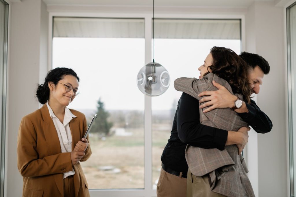 Real Estate Agent smiling while her clients celebrate buying their new home